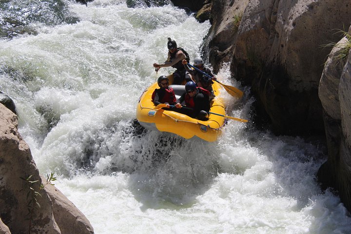 Bote de rafting bajando un rápido entre rocas